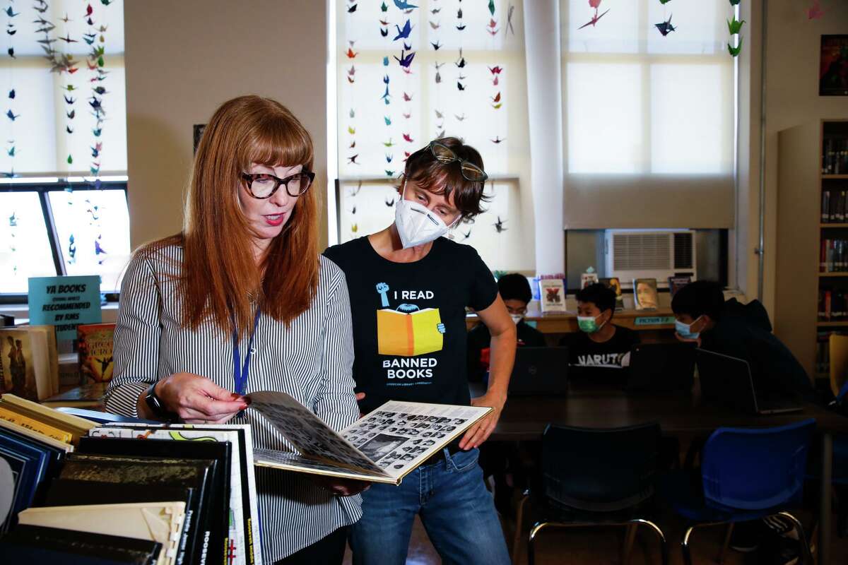 Principal Emily Leicham, (left) and librarian Rachel Clouse look at a yearbook during the eight-grade media class at Roosevelt Middle School in San Francisco.