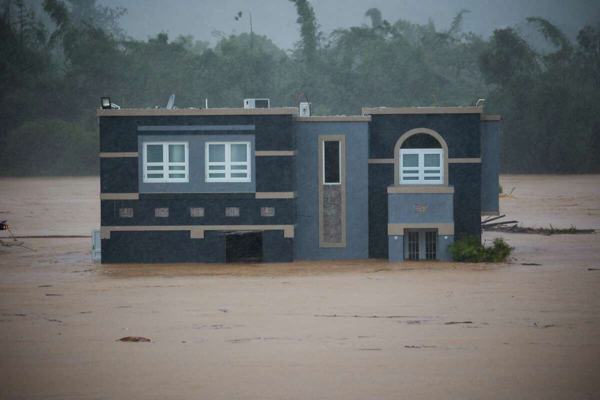 A home is submerged in floodwaters caused by Hurricane Fiona in Cayey, Puerto Rico, Sunday, Sept. 18, 2022. According to authorities three people were inside the home and were reported to have been rescued.
