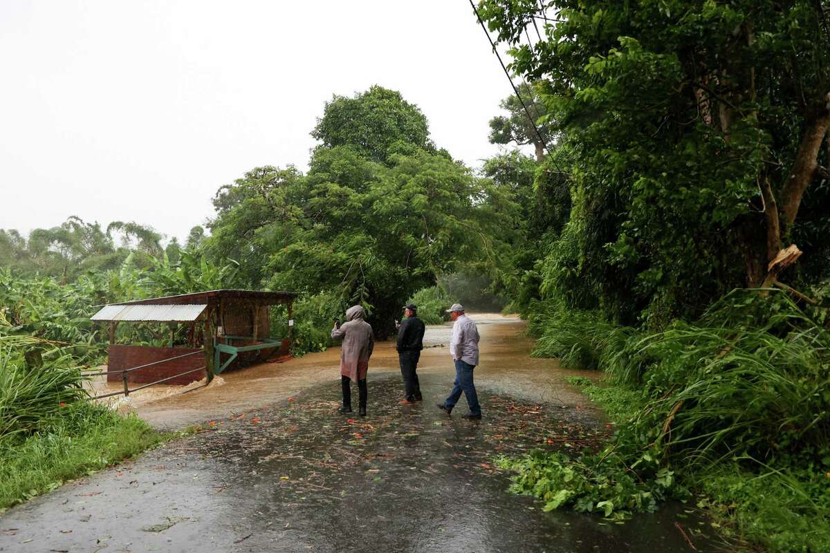 People look at a flooded road during the passing of Hurricane Fiona through Cayey, Puerto Rico, Sunday, Sept. 18, 2022.