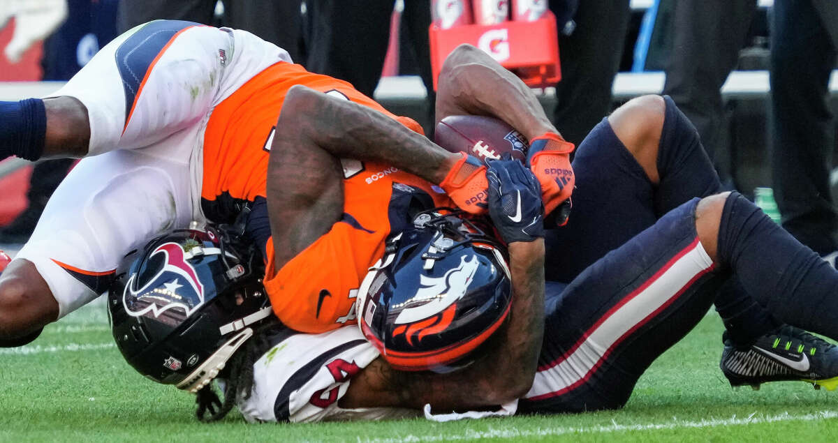 Houston Texans cornerback Derek Stingley Jr. (24) and Denver Broncos wide receiver Courtland Sutton (14) get tangled up as they both come down with the ball during the fourth quarter of an NFL football game Sunday, Sept. 18, 2022, in Denver.