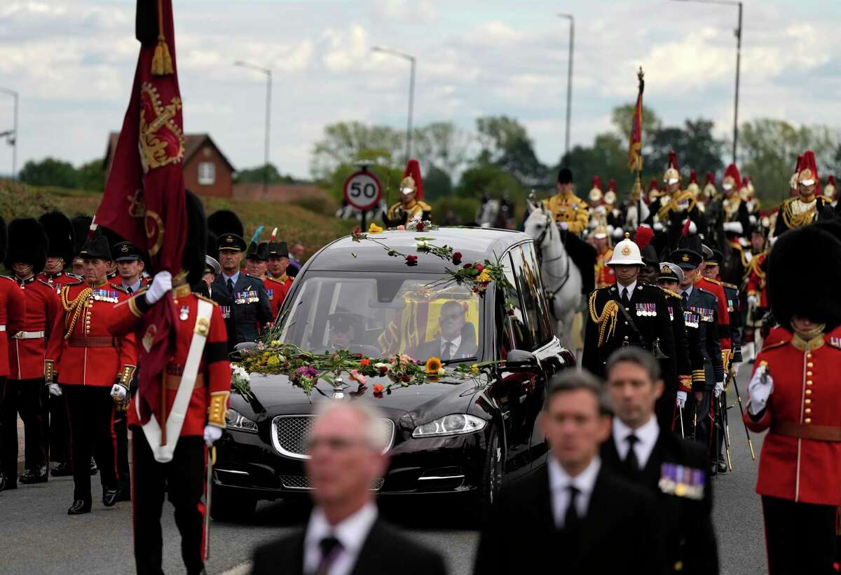 Flowers cover the hearse carrying the coffin of Queen Elizabeth II as it arrives on the Albert Road outside Windsor Castle in Windsor, England, Monday, Sept. 19, 2022. The Queen, who died aged 96 on Sept. 8, will be buried at Windsor alongside her late husband, Prince Philip, who died last year.