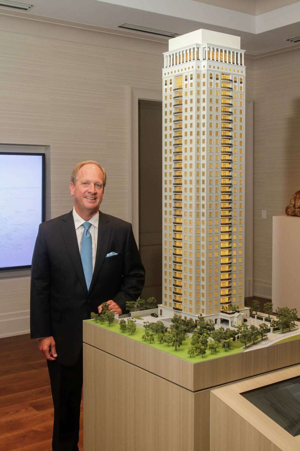 Kendall Miller, the grandson of Tanglewood founder William Farrington, stands next to a model of the proposed high rise from its sales center in Uptown Park.
