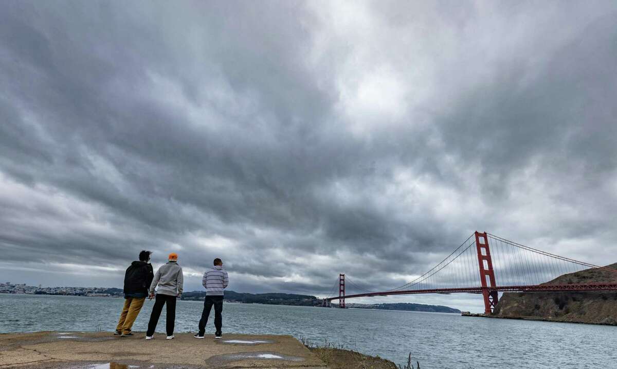 上个星期天，三个男人看着金门大桥，乌云笼罩着。