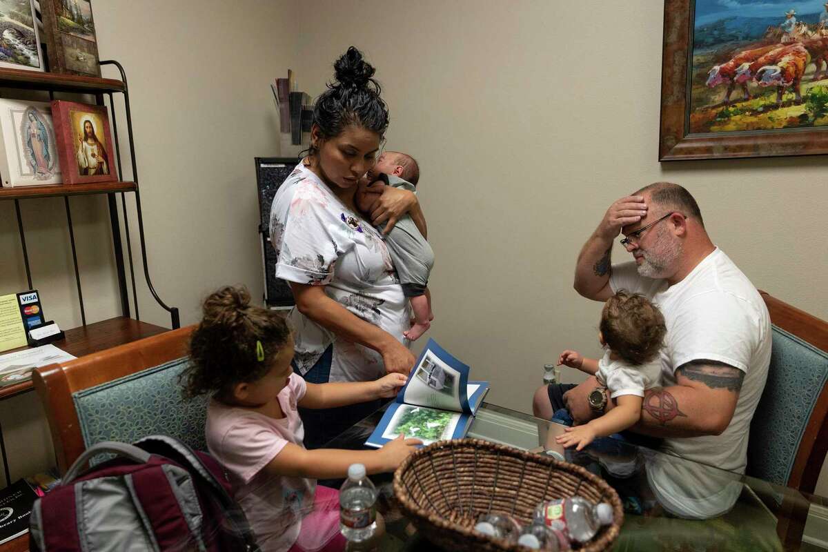Janel Rodriguez, holding her 4-week-old son, Mordecai, helps her daughter, Jolene, read through a book while her husband, Brandon Dunn, sits with their daughter, Alnora. The family was waiting at Harrell Funeral Home in Kyle for Noah’s remains. The 15-year-old died of a fentanyl overdose Aug. 21.