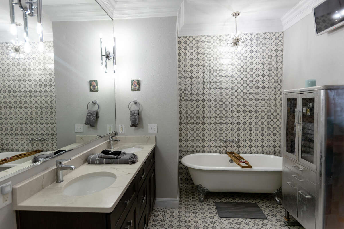The owner's bathroom has been updated with ceramic starburst tiles on the floor running up the wall behind the old style claw foot tub. 