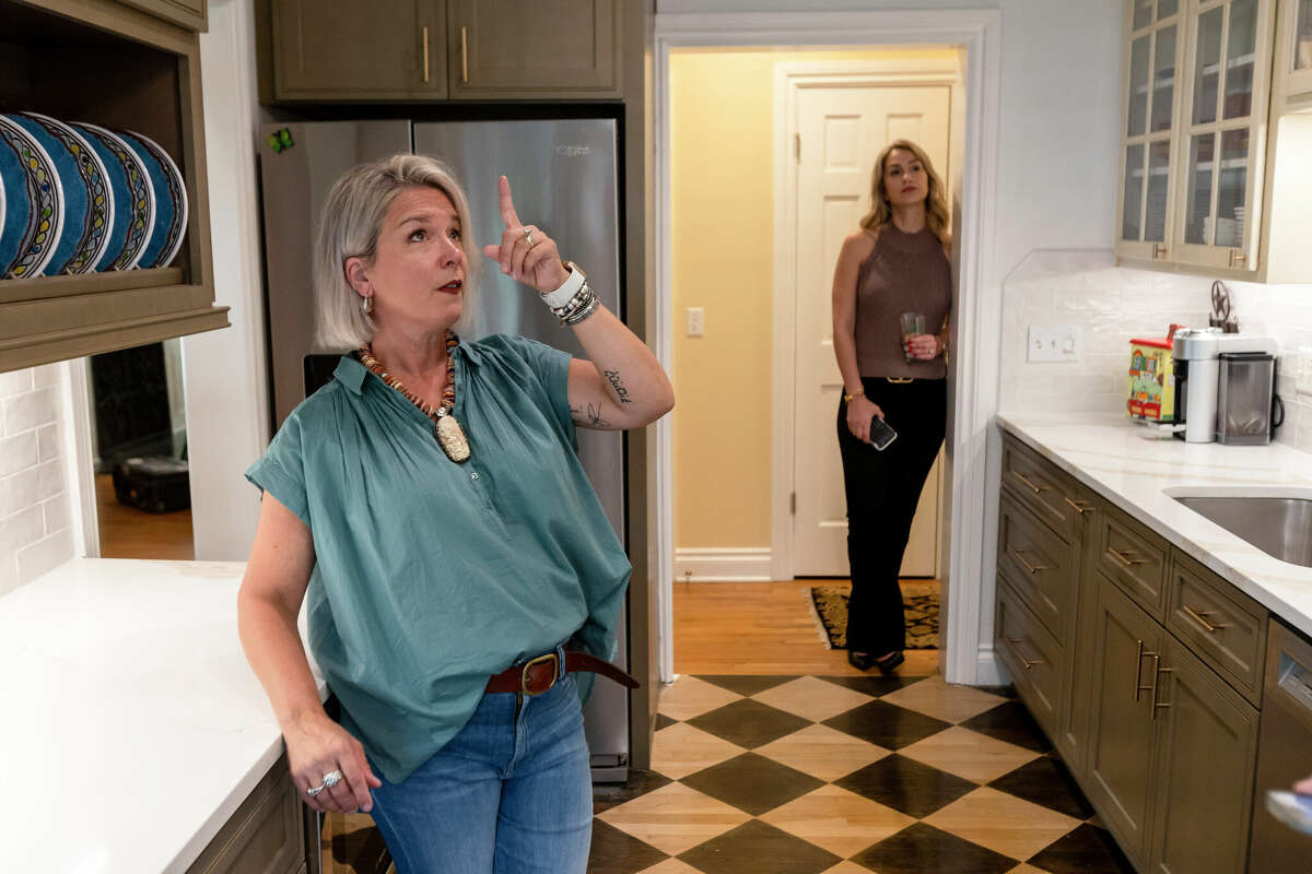 Homeowner Melanie Tucker points out details of the recently renovated kitchen in her Alamo Heights home while designer Monica Beyer looks on.