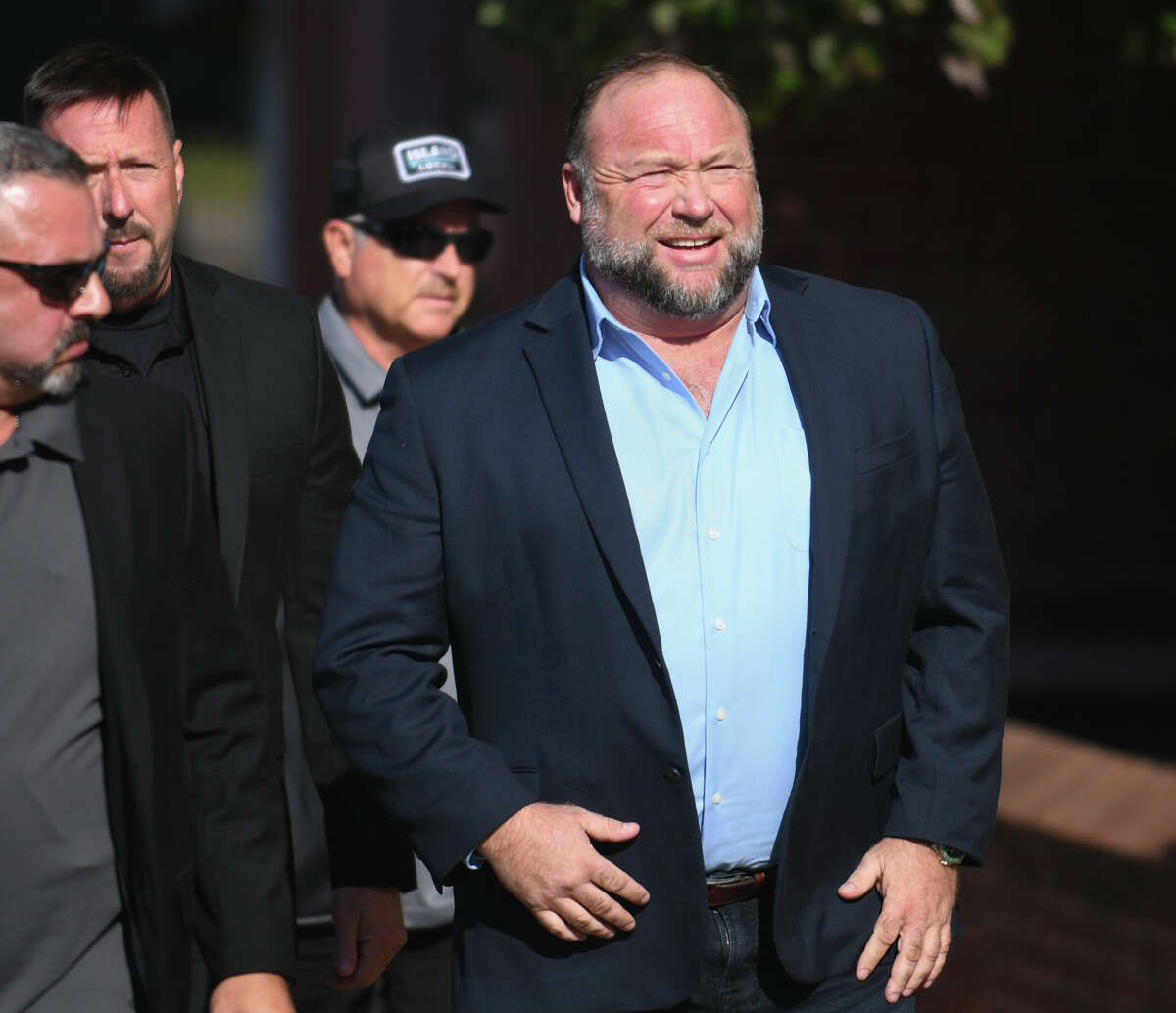 Alex Jones, right, enters court with members of his security team and speaks to the media before attending day five of the Sandy Hook defamation damages trial at Connecticut Superior Court in Waterbury, Conn. Tuesday, Sept. 20, 2022.
