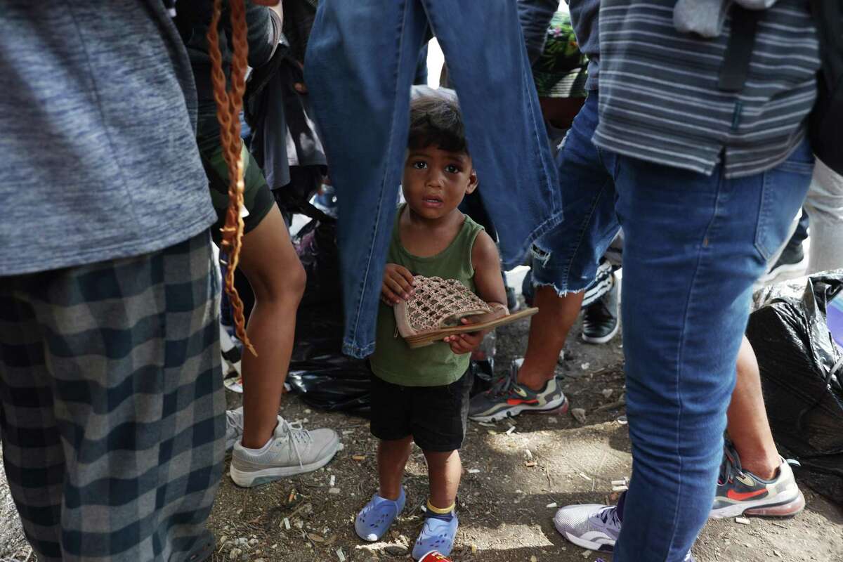 Two-year-old Santiago Lopez find himself in the middle as migrants sort through donated clothes outside San Antonio’s Migrant Resource Center on San Pedro Avenue. The boy and his family are from Venezuela.