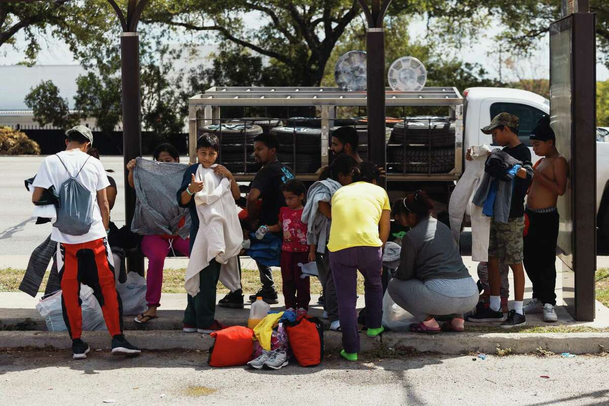 Venezuelan migrants wait at a bus stop across from San Antonio’s Migrant Resource Center after a three-day stay at the facility.