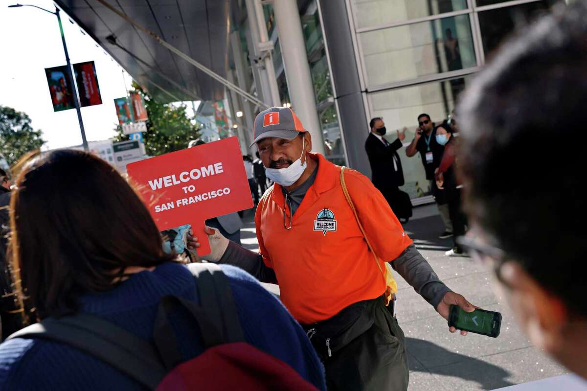 Vidal Rodriguez holds a sign welcoming attendees to registration before the Dreamforce 2022 conference in San Francisco on Tuesday.  Dreamforce 2022 is the biggest conference in San Francisco since the pandemic started.