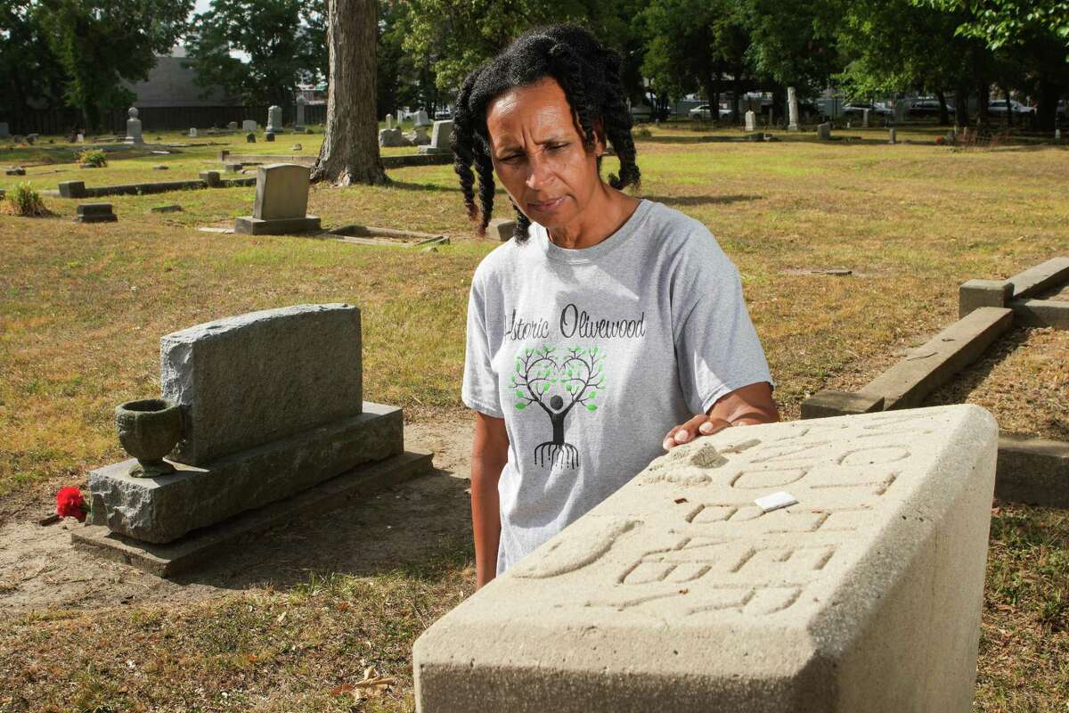 Margott Williams, president of Descendants of Olivewood, poses for a portrait in Olivewood Cemetery. Williams is the president of Descendants of Olivewood, a nonprofit that cares for the historic Black Cemetery. This grave, where 28-year-old Mayme Beauchamp and her day-old daughter is buried, has fascinated her since she first saw it. She said it spurred her to get into the history of the people buried there as well as helping lead the upkeep.