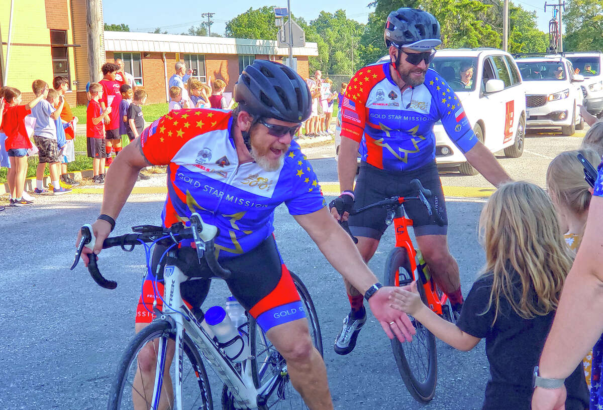 Bike riders give high fives to Virginia Elementary School students as they pass through Virginia on a 500-mile ride to remember fallen heroes and raise support for Gold Star families.