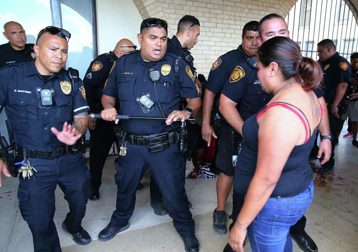 Police form a line around a man who smashed a glass door and cut his arm during a lockdown at Jefferson High School on Tuesday.  The parents confronted the police during the incident.