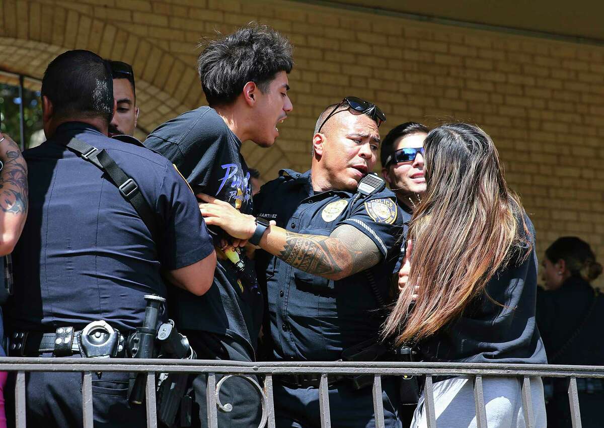 A man is handcuffed as chaos ensues outside Thomas Jefferson High School in San Antonio, after the school went into lockdown on Tuesday, Sept. 20, 2022. Alarmed parents laid siege to the Texas high school Tuesday after a classroom shooting report that ultimately proved to be false. (Kin Man Hui/The San Antonio Express-News via AP)
