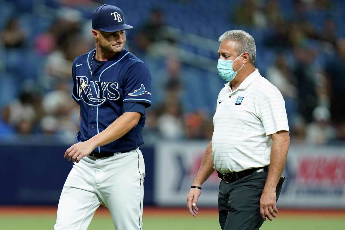 Tampa Bay Rays starting pitcher Shane McClanahan, left, looks back at trainer Mike Sandoval after being taken out of the game against the Houston Astros during the fifth inning of a baseball game Tuesday, Sept. 20, 2022, in St. Petersburg, Fla.