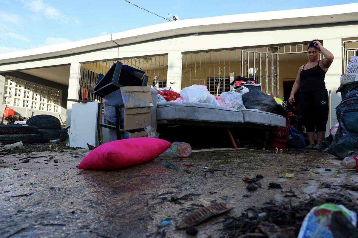A woman looks at her water-damaged belongings after flooding caused by Hurricane Fiona tore through her home in Toa Baja, Puerto Rico, Tuesday, Sept. 20, 2022.
