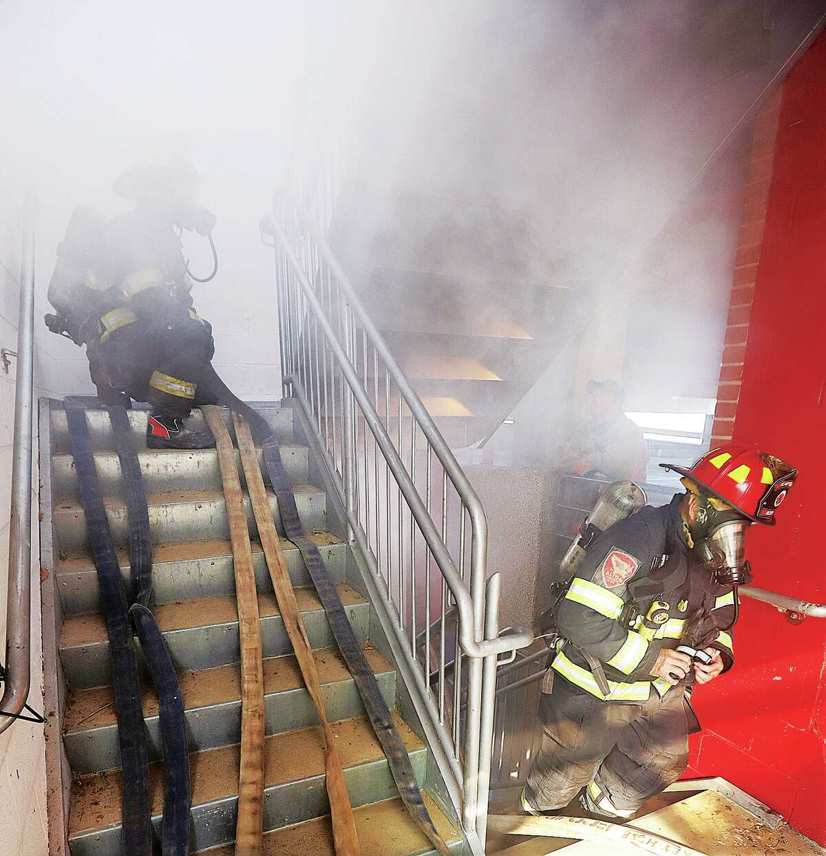 John Badman|The Telegraph Alton firefighters advance a "high-rise pack" of hose up the stairwell in the parking garage at OSF St. Anthony's Health Center in Alton during training Wednesday on fighting high rise fires. 