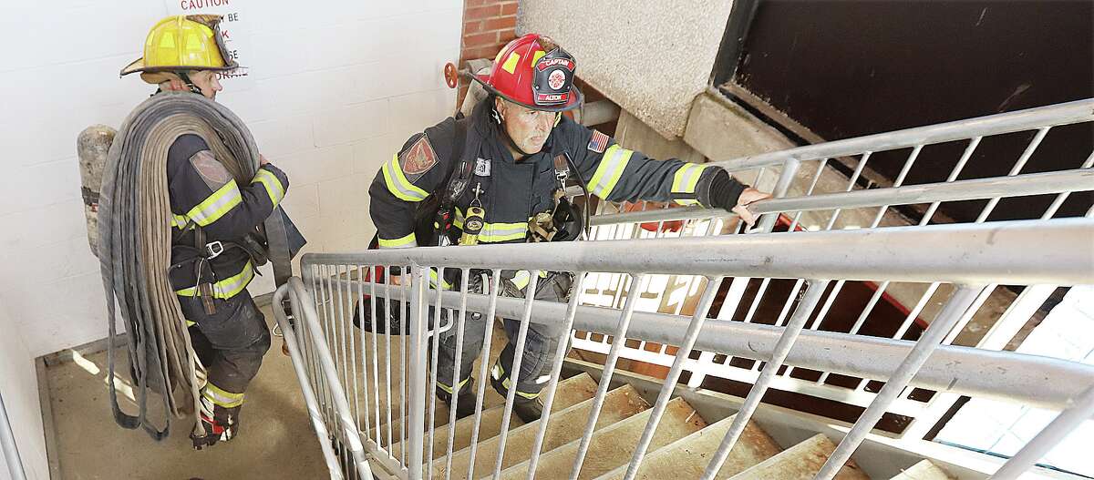John Badman|The Telegraph Alton firefighters carry a "high-rise pack" of hose up a stairwell Wednesday during refresher training.