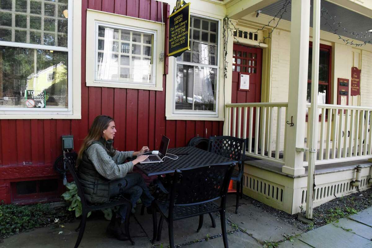 Claire Hardwick works on her laptop outside the Rensselaerville Library where she can get broadband internet access for her job on Wednesday, Sept. 21, 2022, in Rensselaerville, N.Y. Hardwick, a New York based online producer, has been working outside the library since July because she can’t get good internet service at the home she is staying in nearby.