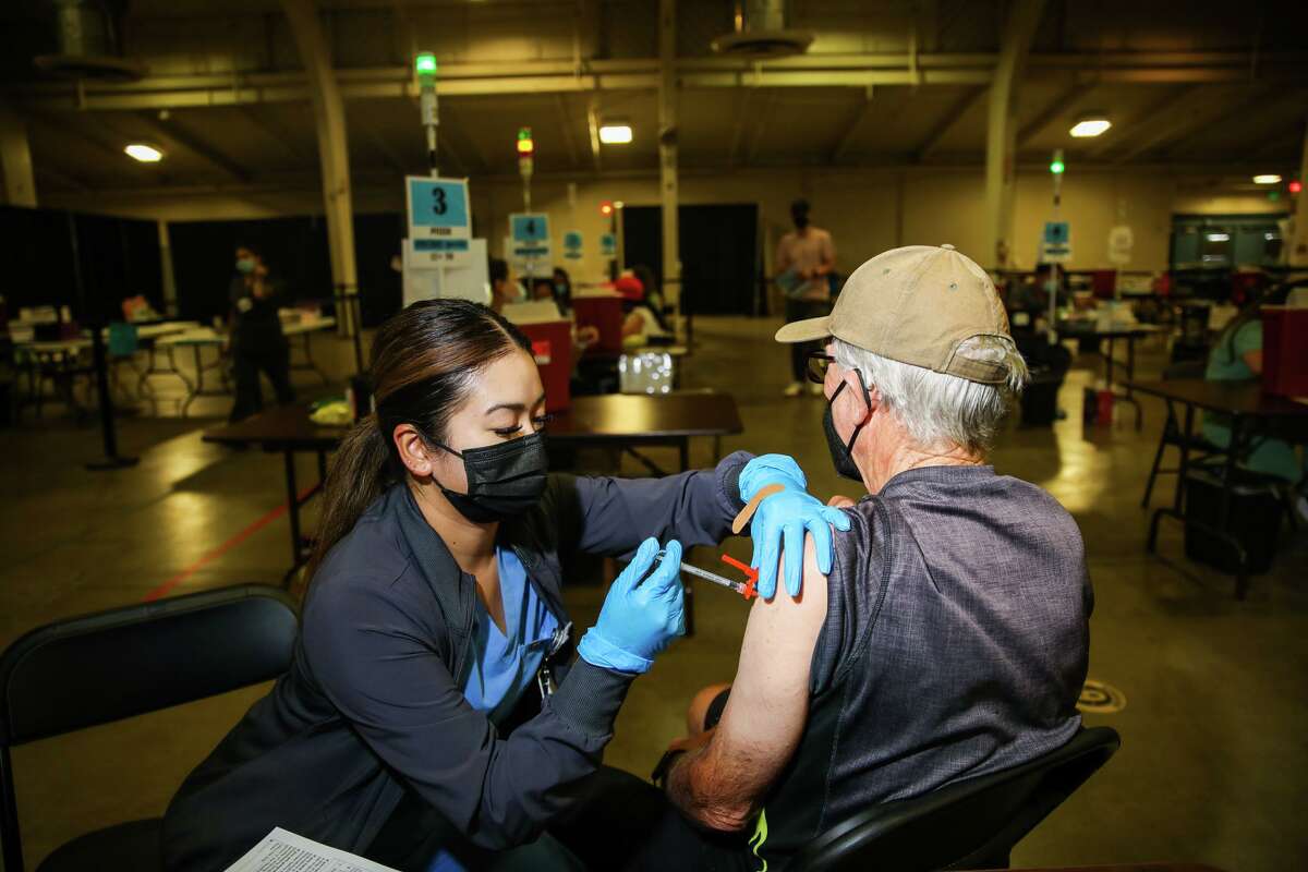 New COVID booster: Should you get the shot if you had symptoms? Jonna Cadilena administers a Pfizer booster shot for Jerry Davis, 77, of San Jose, at the Santa Clara County Fairgrounds.