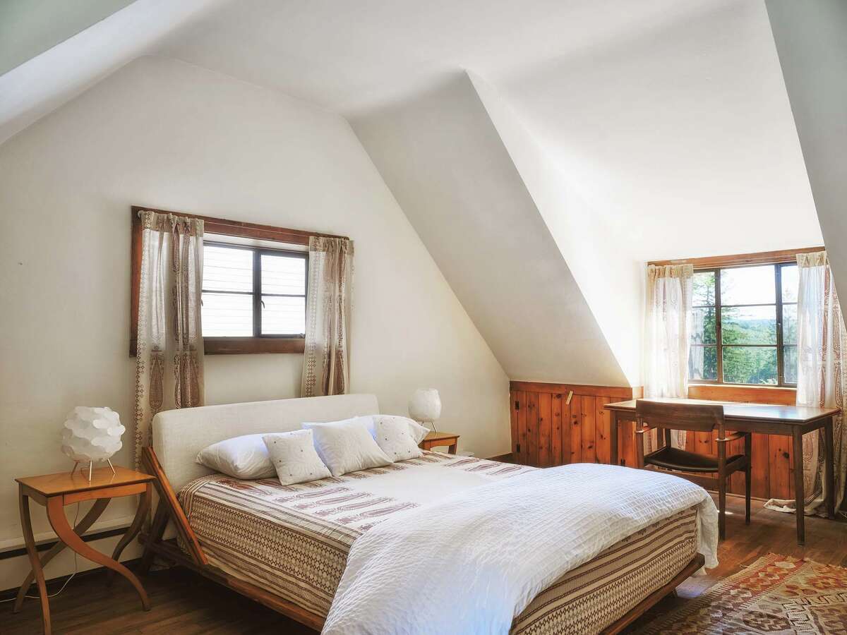A bedroom in the original stone cottage has a clean, contemporary feel that still has a rustic vibe to match the structure and wooded setting.