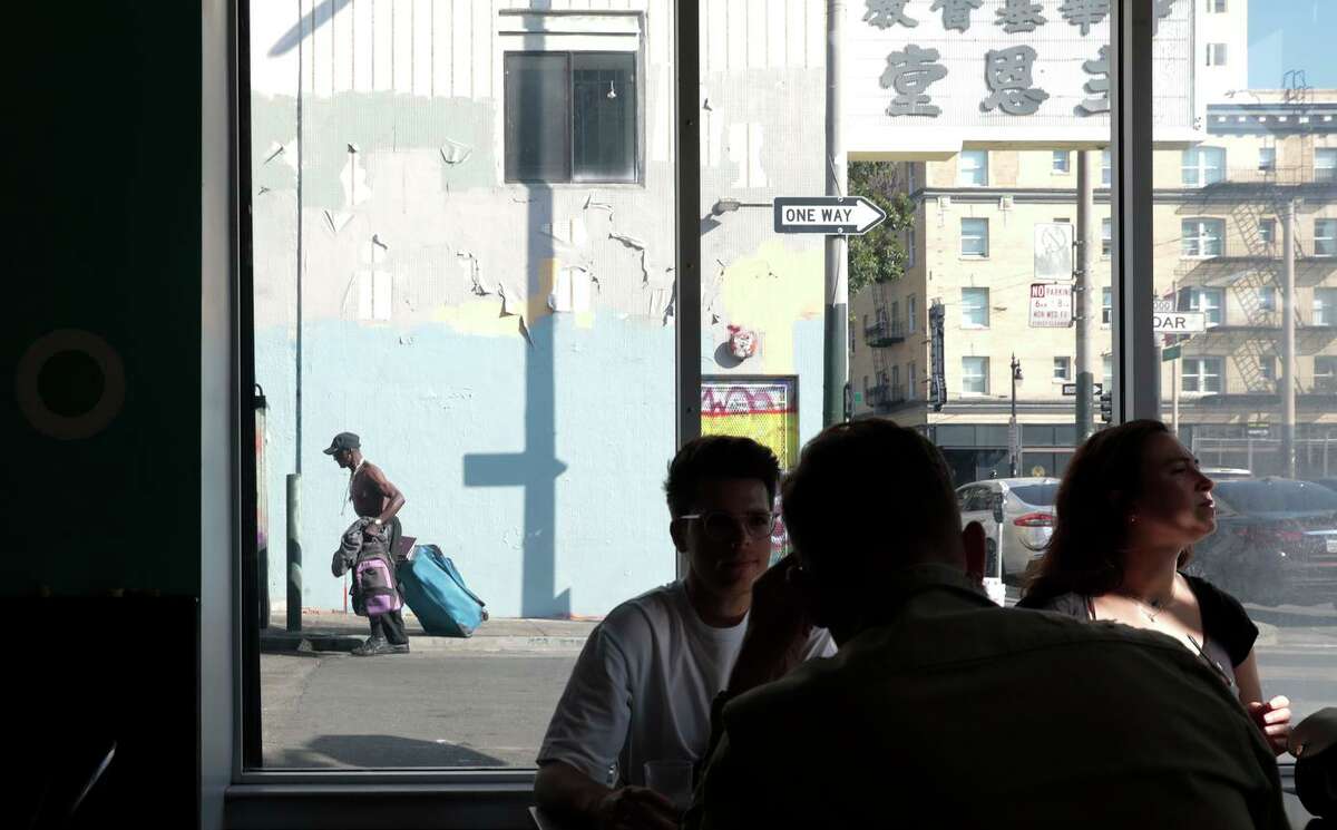 Jane on Larkin的顾客站在一扇窗户前，眺望着旧金山雪松街的小巷。居民们说，下波尔克街附近的犯罪和无家可归者越来越多。