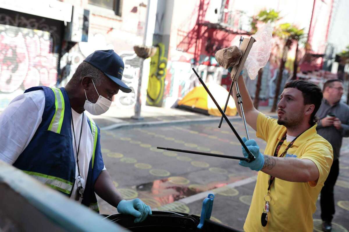 Ronald Reece (left) and Jason Da Silva, community ambassadors, deposit items into a larger garbage bin on Fern Alley in San Francisco. Residents say the Lower Polk Street neighborhood is increasingly dealing with crime and homelessness.
