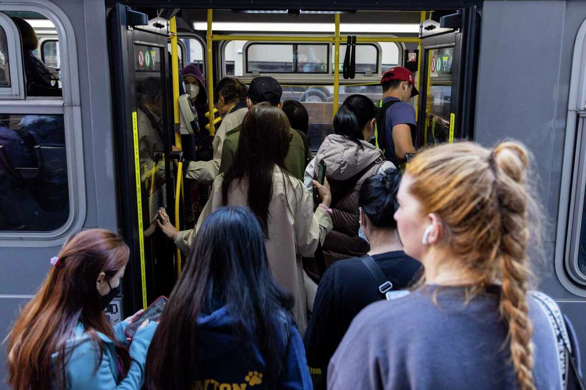 通勤者在旧金山的Kearny和Geary街道上登上Muni巴士的后部。