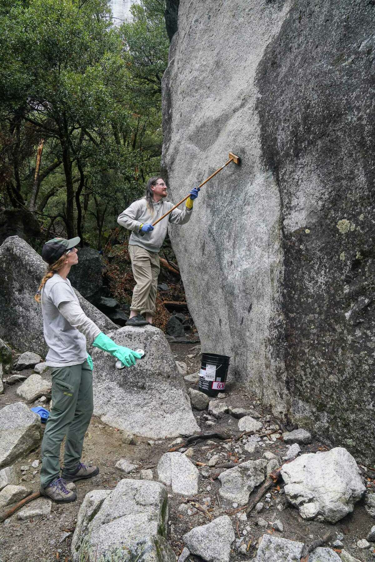 Brendan Smits在优胜美地瀑布小径上的一块巨石上使用涂鸦清除剂。