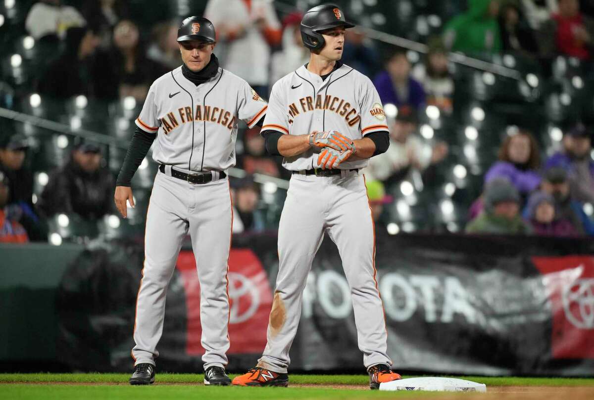 San Francisco Giants third base coach Mark Hallberg, left, congratulates Jason Vosler after his RBI-triple off Colorado Rockies starting pitcher German Marquez in the fourth inning of a baseball game Wednesday, Sept. 21, 2022, in Denver. (AP Photo/David Zalubowski)
