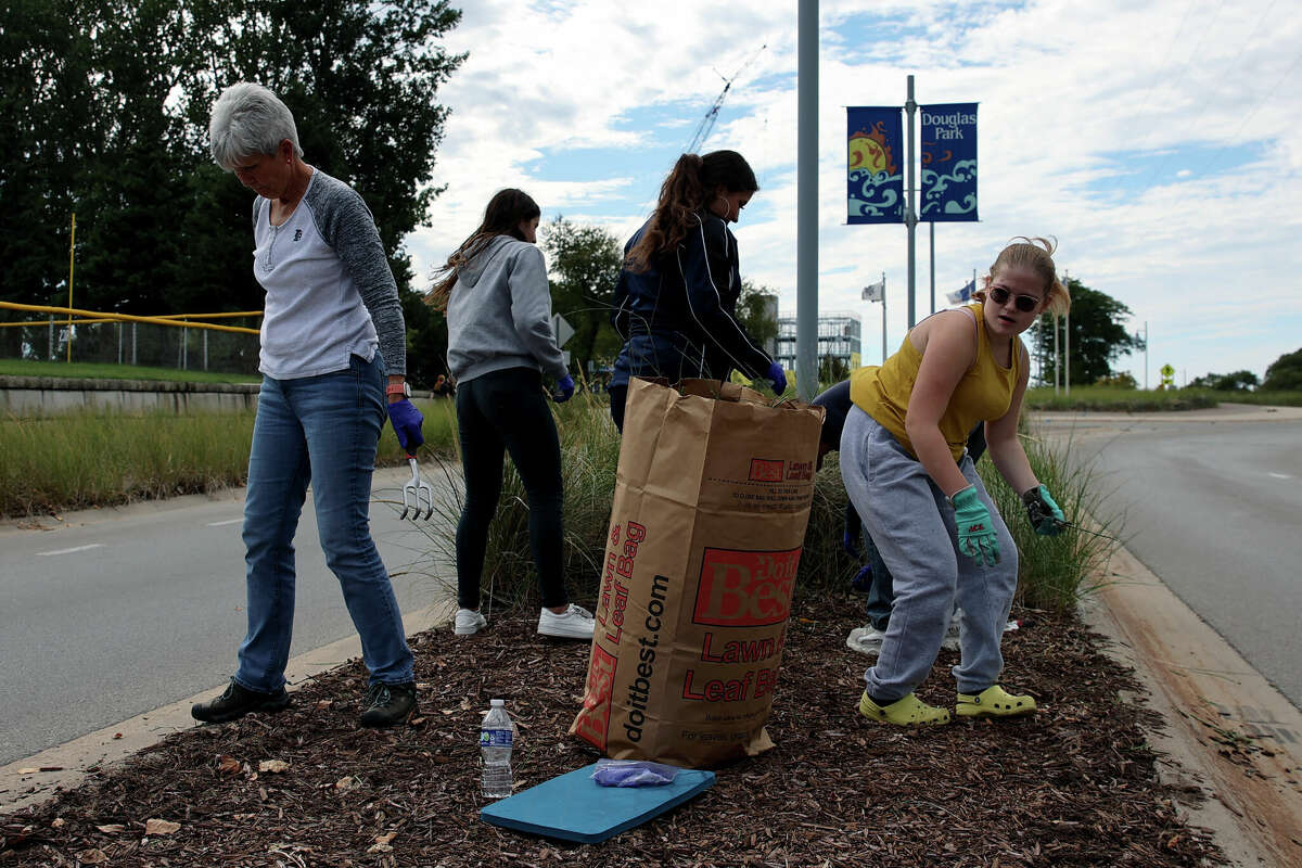 Flynn Anderson (right) and fellow Manistee High School varsity cheerleaders clean up a median across from the softball fields at First and Cherry Street during a Manistee Proud event on Wednesday afternoon. 