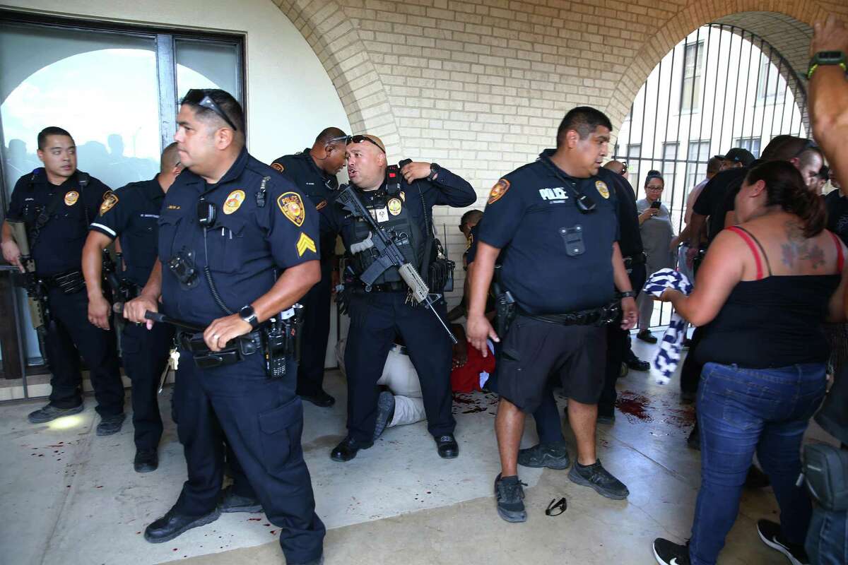Police form a line around a man who cut his arm trying to break through a glass door during a chaotic lockdown at Jefferson High School on Tuesday. Parents swarmed the grounds and shouted at police, irate that their children couldn’t leave. It took more than an hour for officers to search the building and conclude that reports of gunfire had been a false alarm.