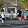 Cars line up at the gate as a jogger shows his park pass during the reopening of Greenwich Point Park in Old Greenwich, Conn. Thursday, May 7, 2020. After nearly six weeks of being closed, Tod's Point reopened Thursday to a line of about 30 cars ready to enter as the gate opened at 7 a.m. The park is limited to a capacity of 500 cars with the water is off-limits, along with the picnic tables, benches, grills and playground areas.