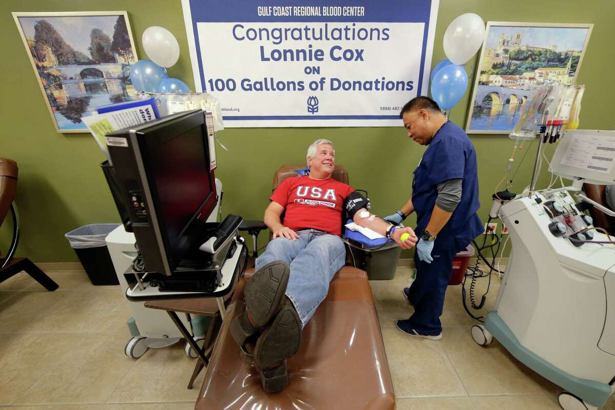 Technician Proceso Peria, right, makes sure Lonnie Cox, left, is comfortable as Cox sits for his 100th gallon of blood donation.