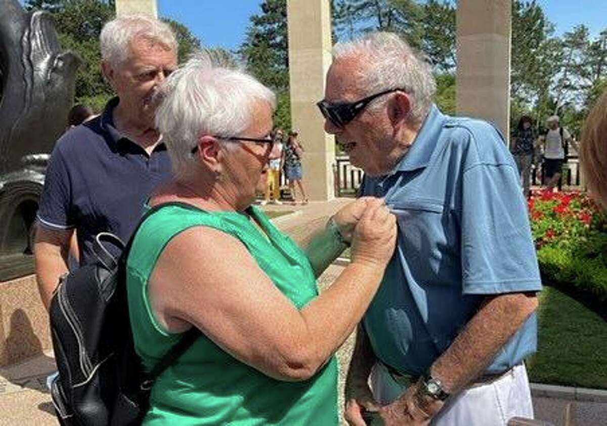Alice Maret-Guelph, president of a Normandy organization, pins a medal on Stamford, Conn., resident Charlie Guinta at the Normandy Cemetery for his service during World War II.