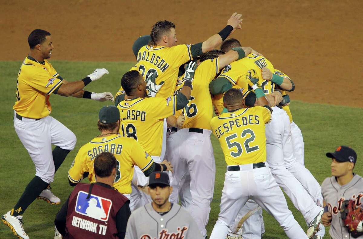 The A’s Stephen Vogt is mobbed by teammates after his game-winning hit drove in Yoenis Cespedes in the bottom of the ninth inning against Detroit in Game 2 of a 2013 American League Division Series at the Coliseum.