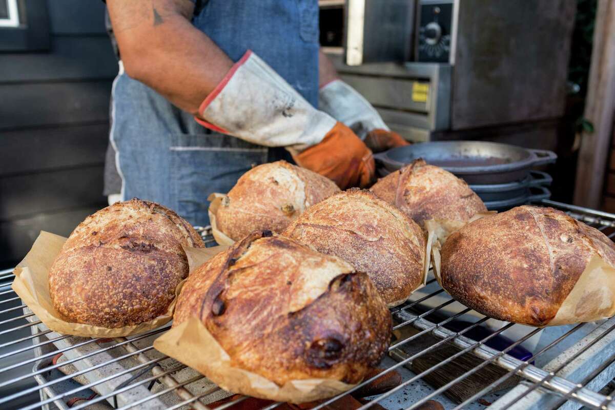 Azikiwee Anderson of Rize Up Sourdough removes loaves from his S.F. backyard oven and places them on a cooling rack in 2020.
