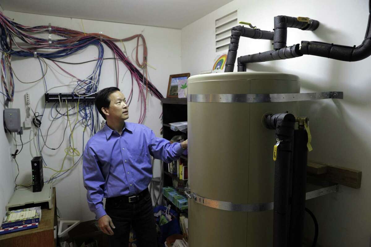 Lafayette City Council Member Wei-Tai Kwok shows the water tank that is heated with electricity at his home, where he has stopped using natural gas.