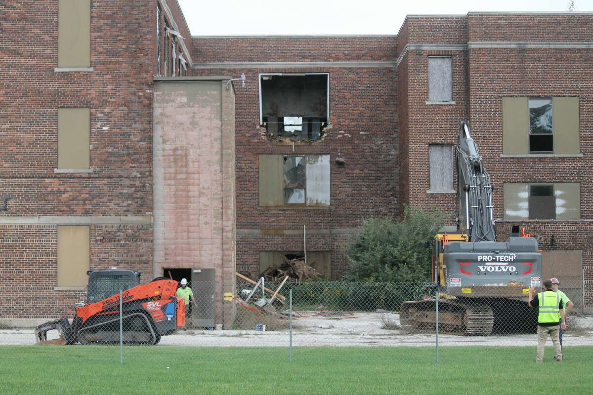 Workers from Pro-Tech Environmental and Demolition, Inc., of Grand Rapids, begin razing the former Manistee High School building Wednesday.