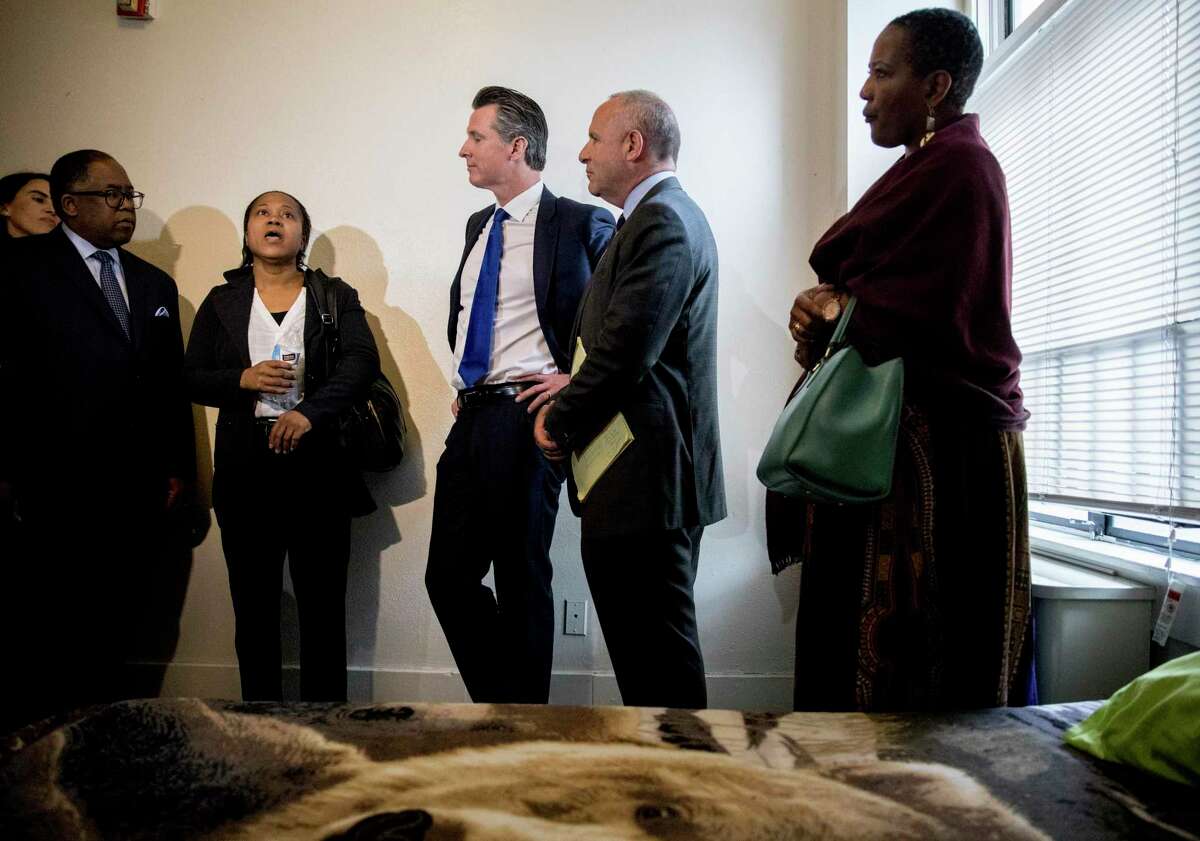 California Governor Gavin Newsom (center) and Sacramento Mayor Darrell Steinberg (second from right) meet tour rooms at the the Henry Robinson Multi-Service Center before a press conference announcing a newly created state-level homeless commission alongside Oakland Mayor Libby Schaaf and other Alameda County and state officials in Oakland in 2019.