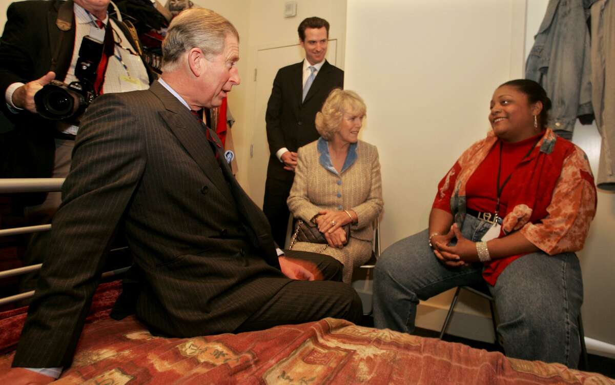 Then-Prince Charles speaks with Renee McIntyre, a formerly homeless woman, seated right, about homelessness in America inside McIntyre’s room at the Empress Hotel in San Francisco. Camilla, Duchess of Cornwall, second from right, and San Francisco Mayor Gavin Newsom, third from right, listen in.