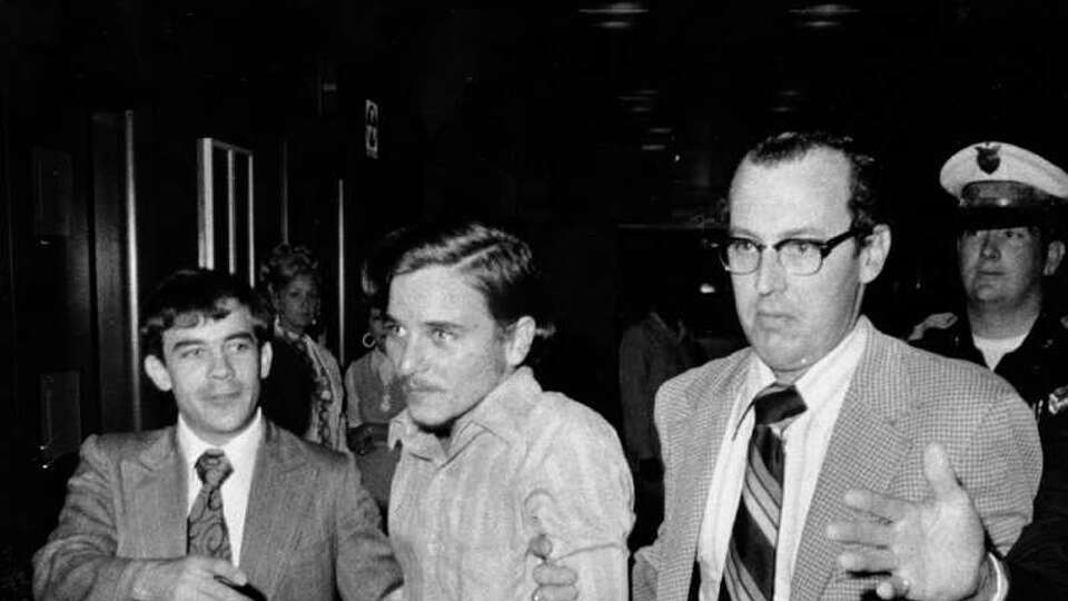 Elmer Wayne Henley, handcuffed, is escorted by police officers into a courtroom in August 1973 to face murder charges after he killed Dean Arnold Corll, who abducted, raped, tortured and murdered at least 28 young men from December 1970 to July 1973. Henley was sentenced to life in prison for his role in the crimes.