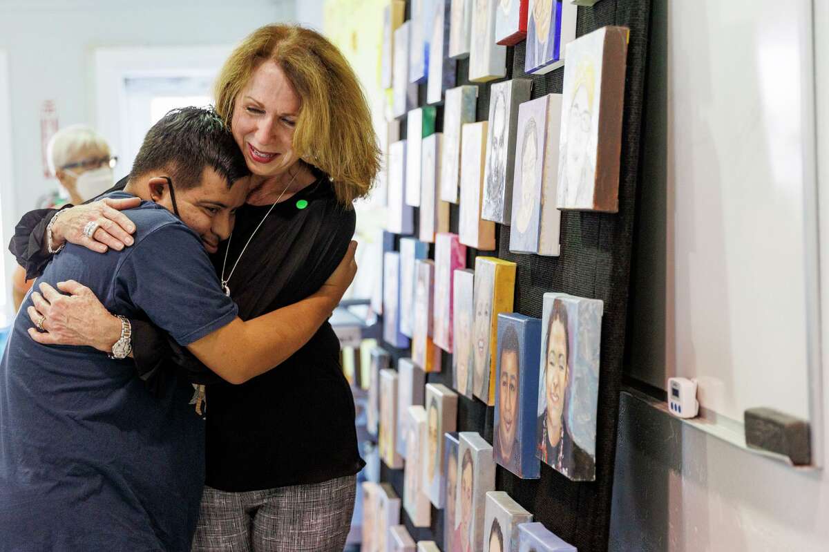 Artist Liliana Clark receives a hug from Johnny, one of the adult life enrichment program participant’s who had his picture painted, during the art unveiling event at the Arc of San Antonio on Friday morning. Dozens of artists from the Coppini Academy of Fine Arts painted 50 portraits of the program’s members.