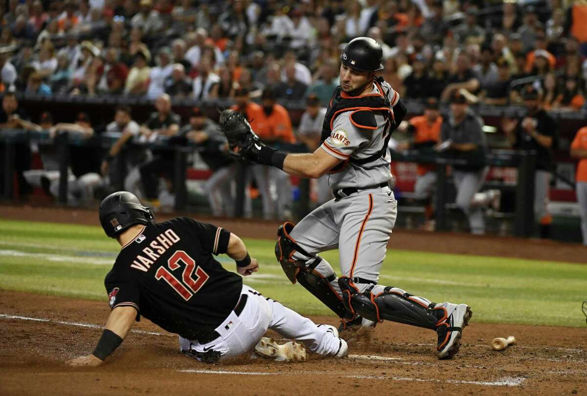 PHOENIX, ARIZONA - SEPTEMBER 24: Daulton Varsho #12 of the Arizona Diamondbacks slides safely into home ahead of the tag by Joey Bart #21 of the San Francisco Giants during the fourth inning at Chase Field on September 24, 2022 in Phoenix, Arizona. (Photo by Norm Hall/Getty Images)