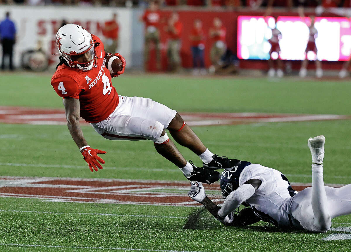 Ta'Zhawn Henry #4 of the Houston Cougars is tripped up by George Nyakwol #20 of the Rice Owls in the fourth quarter.