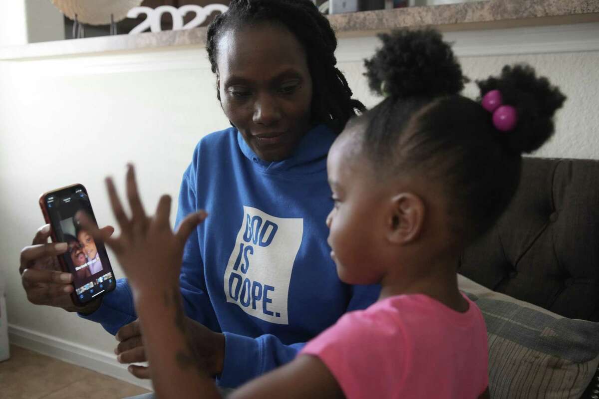 Loutrina Reed shows one of her twin 2-year-old granddaughters, Paige, a video of her late mother Monday, Sept. 12, 2022 in Houston. Reed is now raising the girls after their mother was killed in a shooting. The girls’ mother, Chant’e Mahogany Wilson, 20, was killed on Aug. 8, leaving behind three children. Reed is now raising her son’s twins, in addition to seven of her own children.