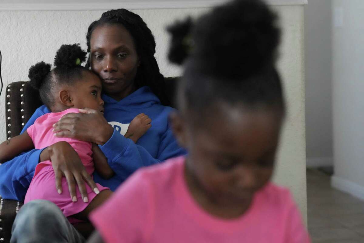Loutrina Reed holds one of her twin 2-year-old granddaughters, Paige, as her sister, Mariah, plays Monday, Sept. 12, 2022 in Houston. Reed is now raising the girls after their mother was killed in a shooting. The girls’ mother, Chant’e Mahogany Wilson, 20, was killed on Aug. 8, leaving behind three children. Reed is now raising her son’s twins, in addition to seven of her own children.