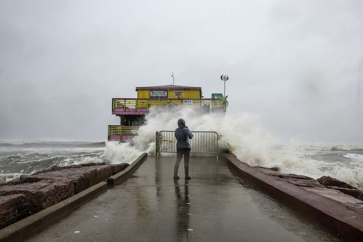 A woman takes photos of waves from the 61st Street Fishing Pier as the outer bands of Hurricane Delta pass through on October 09, 2020 in Galveston, Texas.