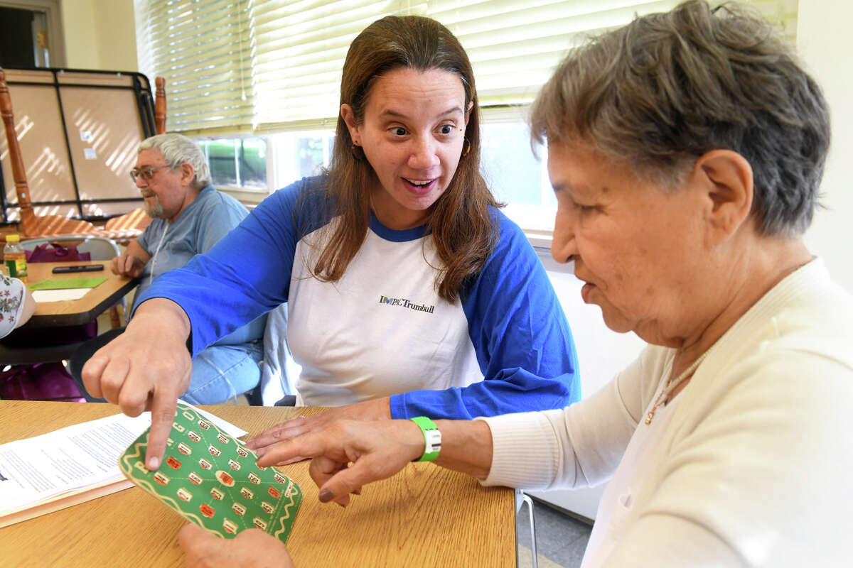 IMPACTrumbull founder Jenn Record sits with Svetlana Andrivsky as she plays bingo during a Sweets and Treats event at the Trumbull Senior Center, in Trumbull, Conn. Sept. 26, 2022.