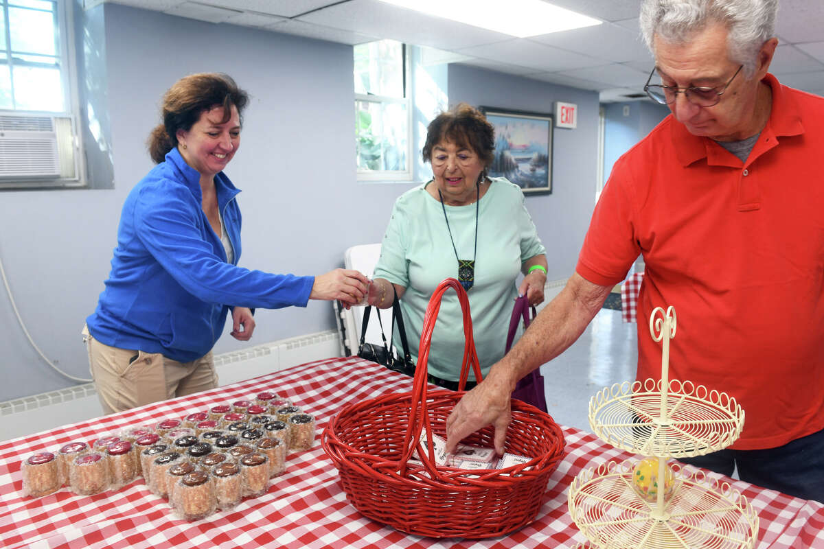 From left, volunteers Dave Record, Nate France and Kristine Saccone sort a wide variety of items to be given out during IMPACTrumbull’s Sweets and Treats event at the Trumbull Senior Center, in Trumbull, Conn. Sept. 26, 2022.